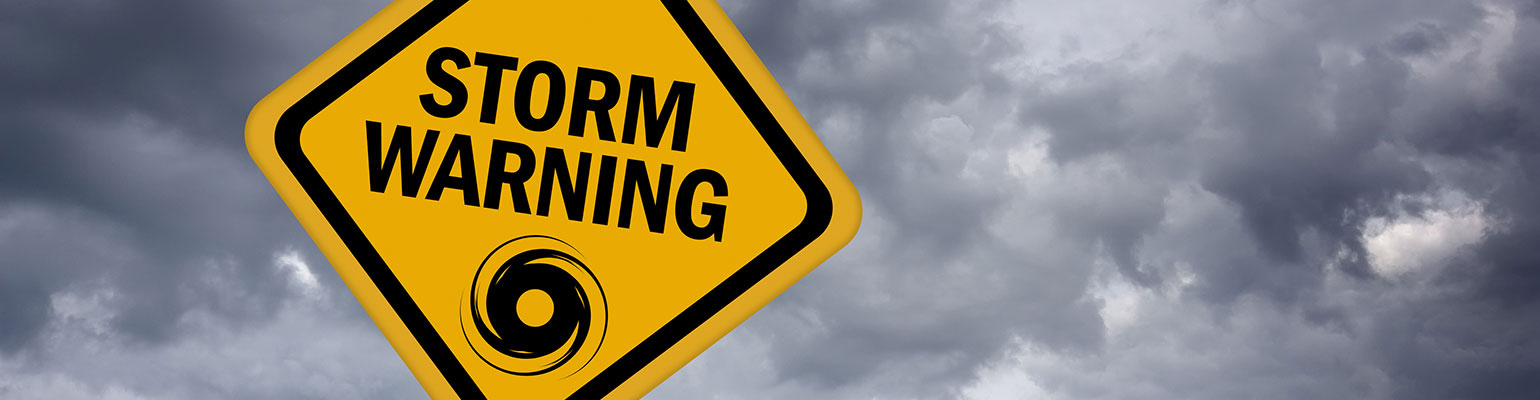 A cloudy, threatening sky and a caution sign that says "Storm Warning"