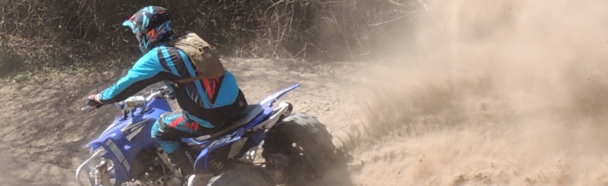 A person riding on an ATV on a dirt track in a forest