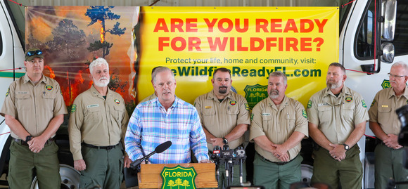 Commissioner Simpson speaking at a press conference surrounded by Forestry personnel