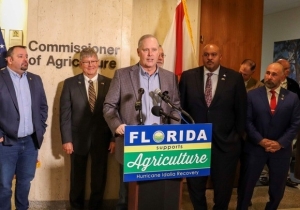 Commissioner Simpson at a podium surrounded by legislative and agricultural leaders